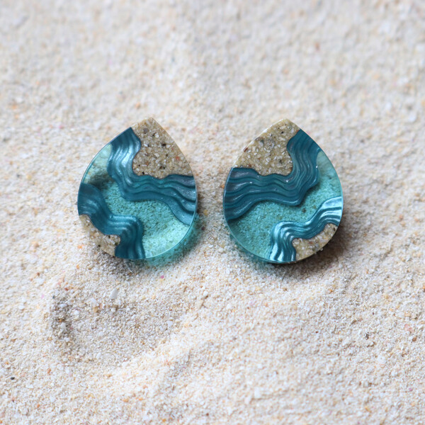 Light blue stud earrings on sand