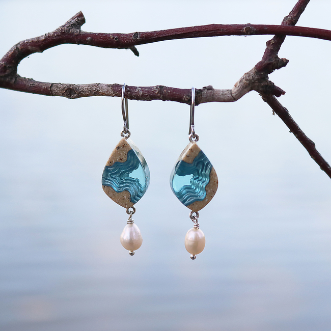 Bay small beach sand and pearl dangle earrings on branch with water in background