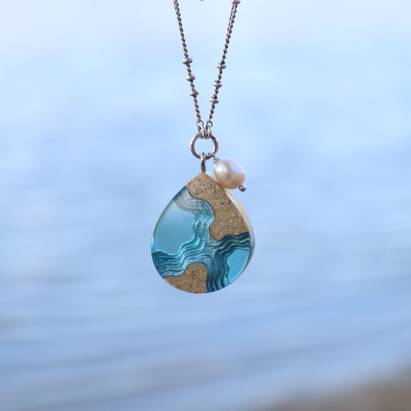 Tombolo small beach sand and blue resin necklace on water