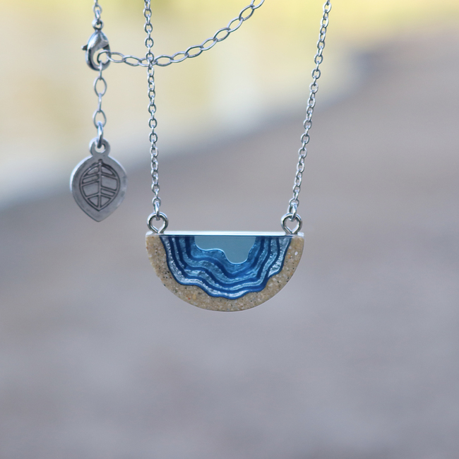 Dainty beach sand and blue resin necklace on beach