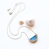 Dainty beach sand and blue resin necklace with white background